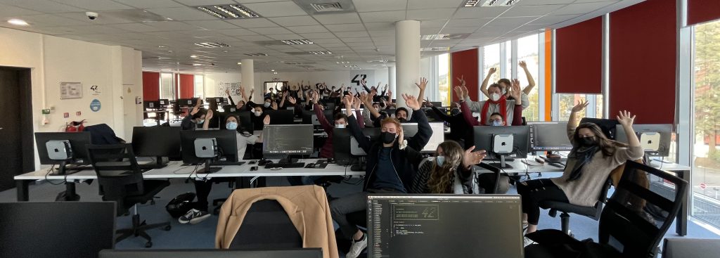 Vie étudiante - Photographie d'étudiants les mains en l'air dans un cluster des locaux de 42 Nice Région-Sud.